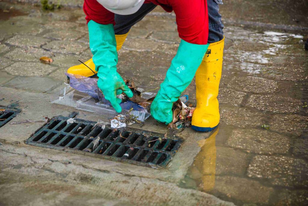 Un trabajador de Interagua saca basura de una alcantarilla en una de las zonas donde se registraron inundaciones. 