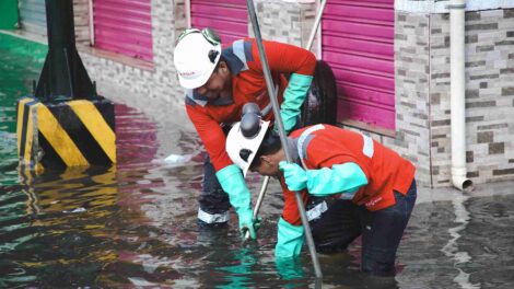 Personal de Interagua intenta destapar una alcantarilla para que desfogue el agua retenida.