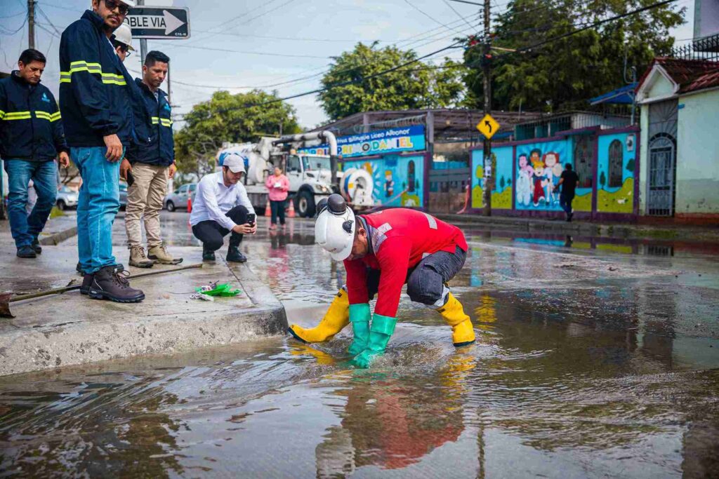 Un trabajador de Interagua limpia una alcantarilla tras la acumulación de agua a causa de las lluvias. 