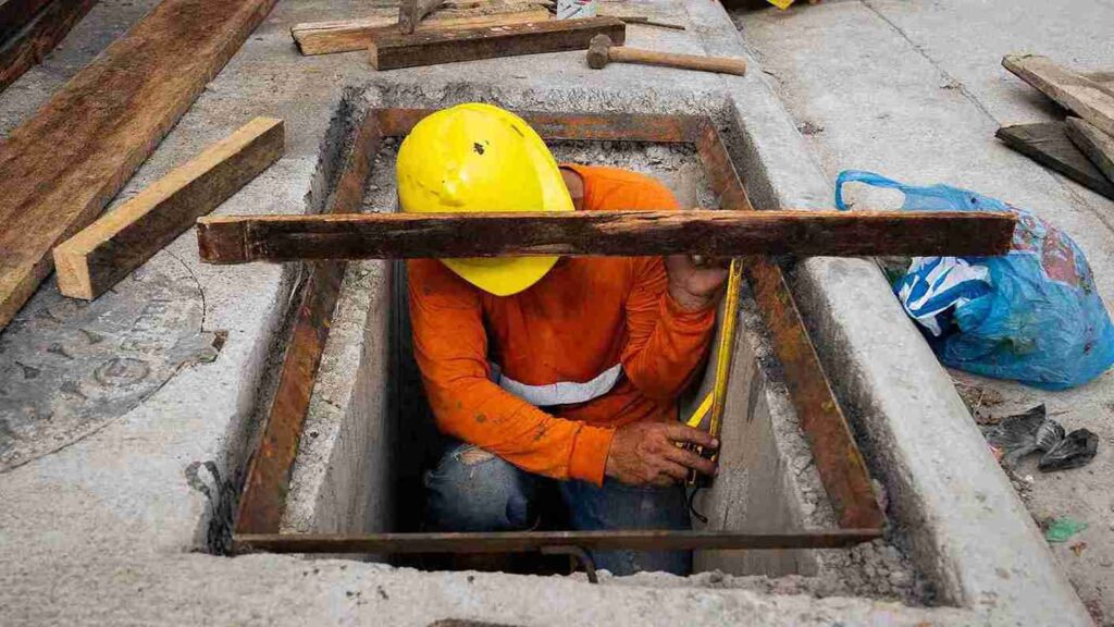 Un obrero realiza trabajos en el sistema de aguas servidas. 