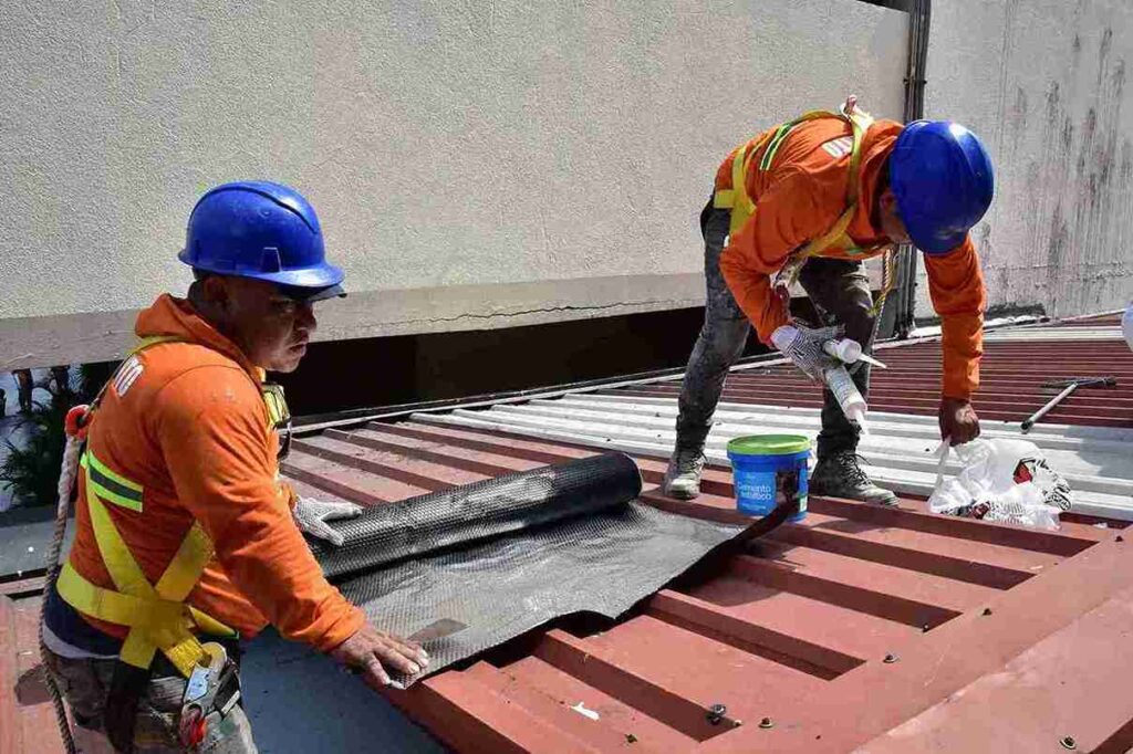 Dos obreros municipales dan mantenimiento a la estructura de los locales comerciales de la Bahía. 