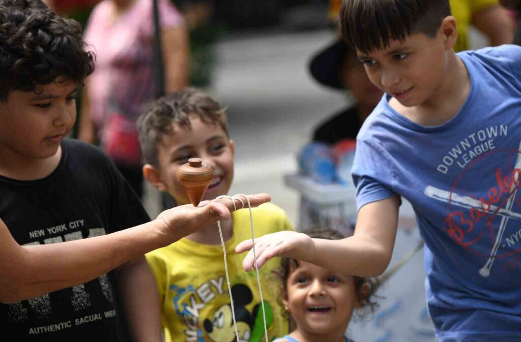 Niños hacen bailar un trompo en la mano, durante la jornada que se realizó en la calle Panamá. 