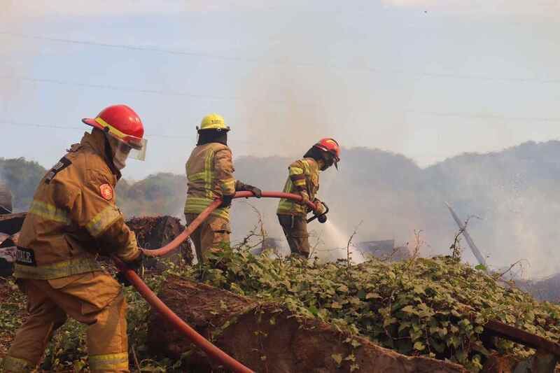 Tres bomberos intentan sofocar el fuego con la ayuda de una manguera.