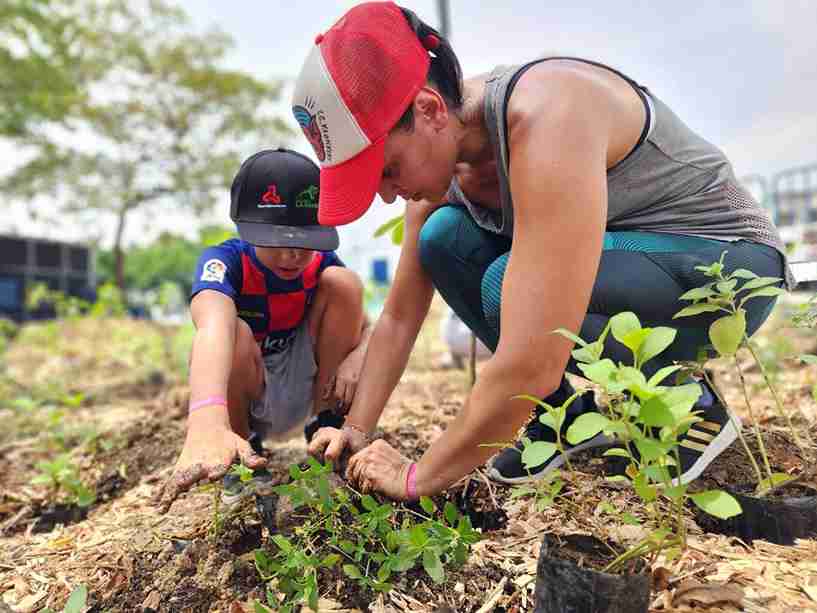 Una madre y su hijo participan en la siembra de árboles nativos en Guayaquil.