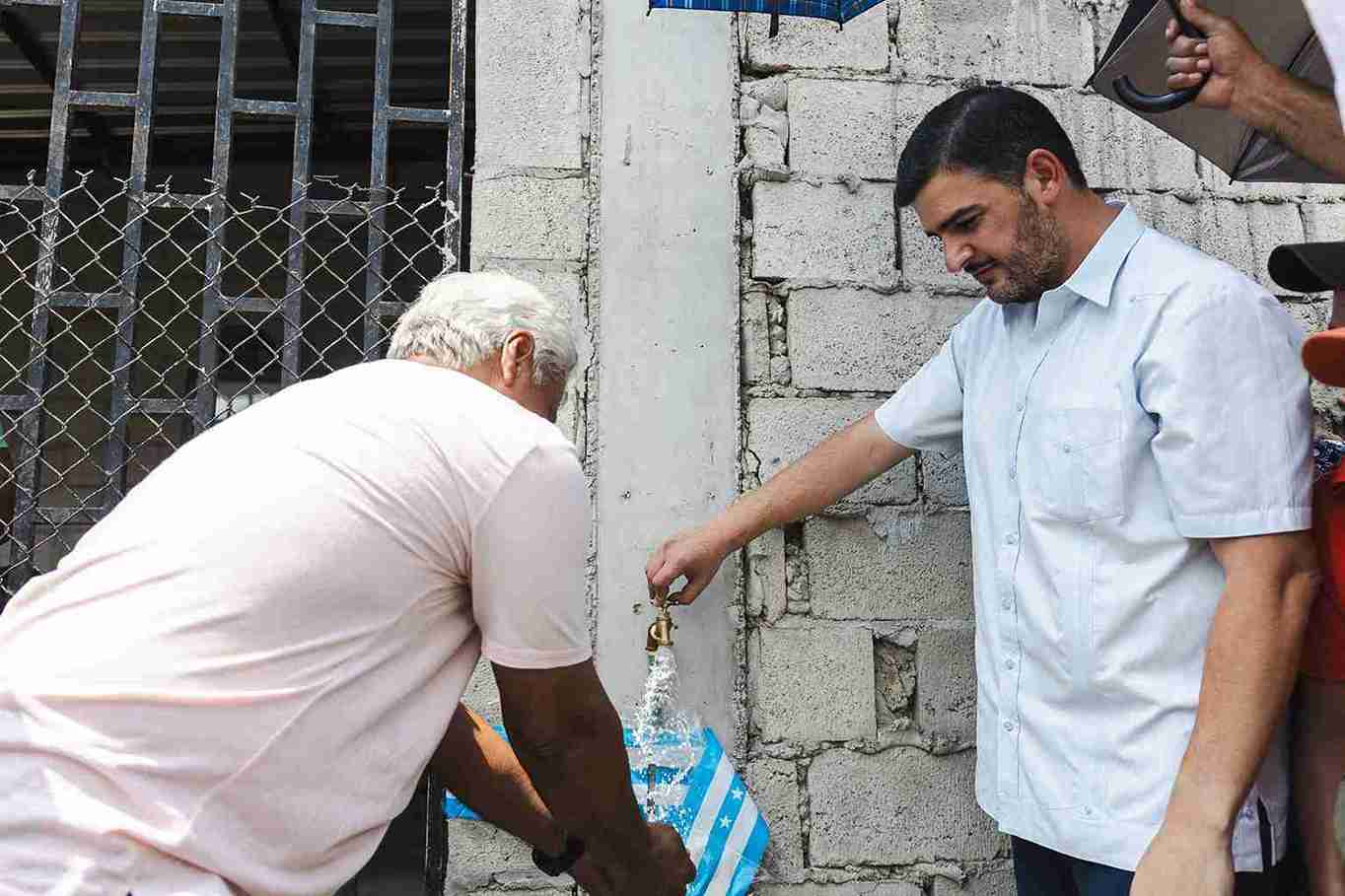 El alcalde Aquiles Alvarez abre una de las llaves del nuevo sistema de agua potable.