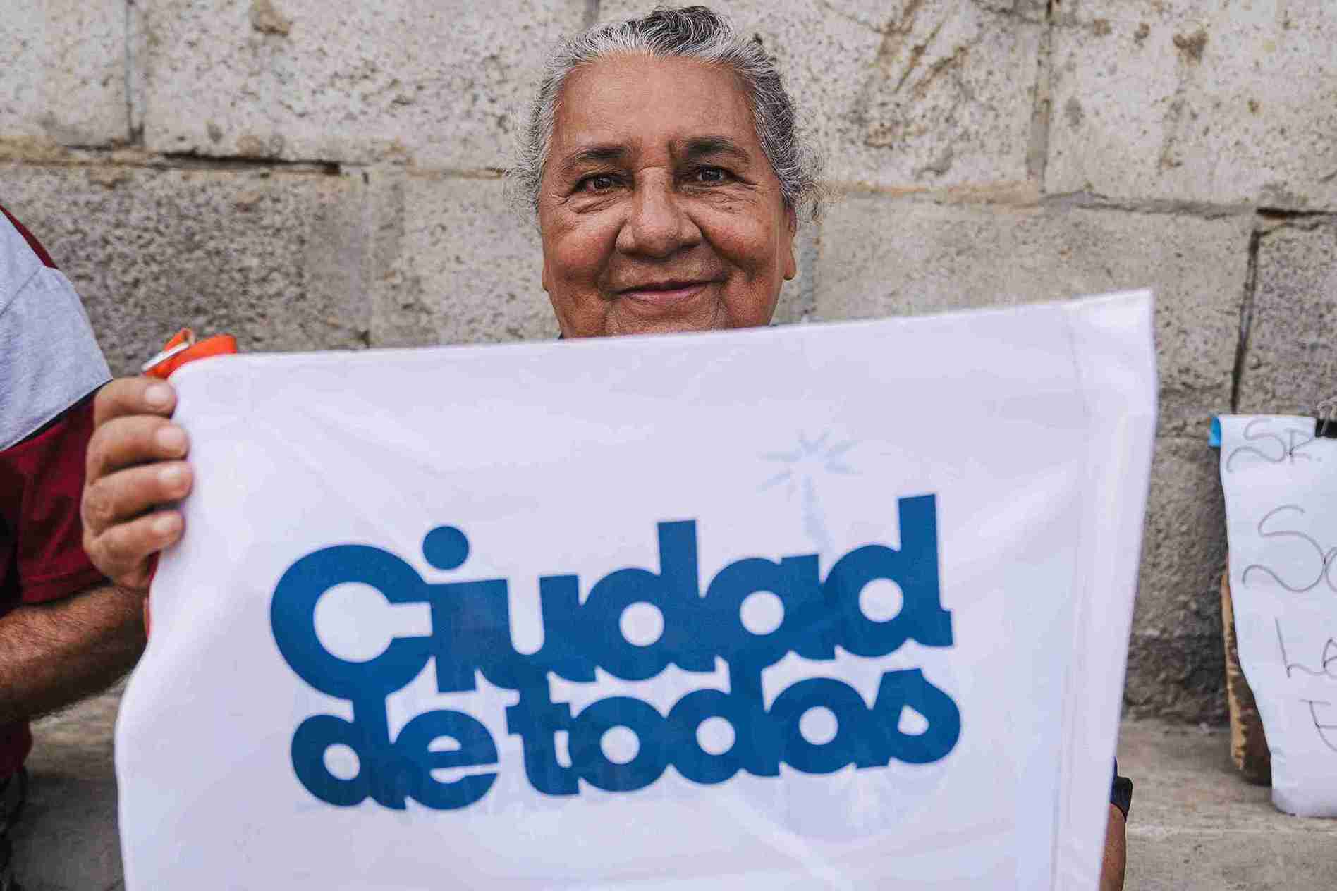 Una ciudadana muestra una bandera con la frase Ciudad de Todos.