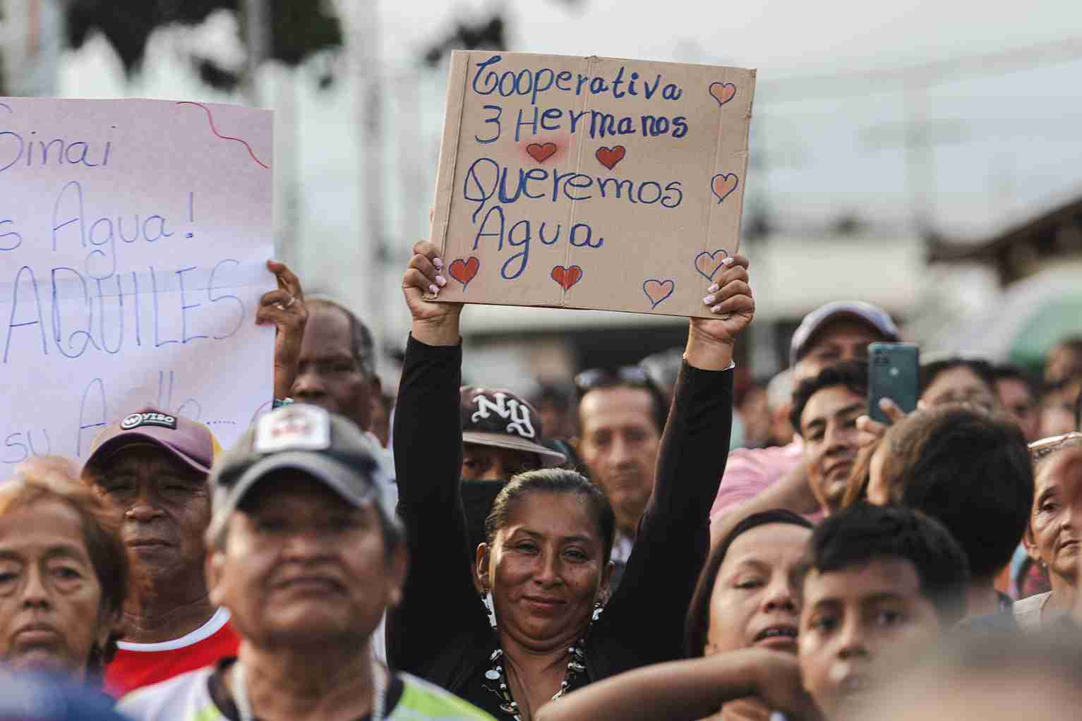 Una ciudadana muestra un cartel exigiendo agua para la cooperativa 3 Hermanos