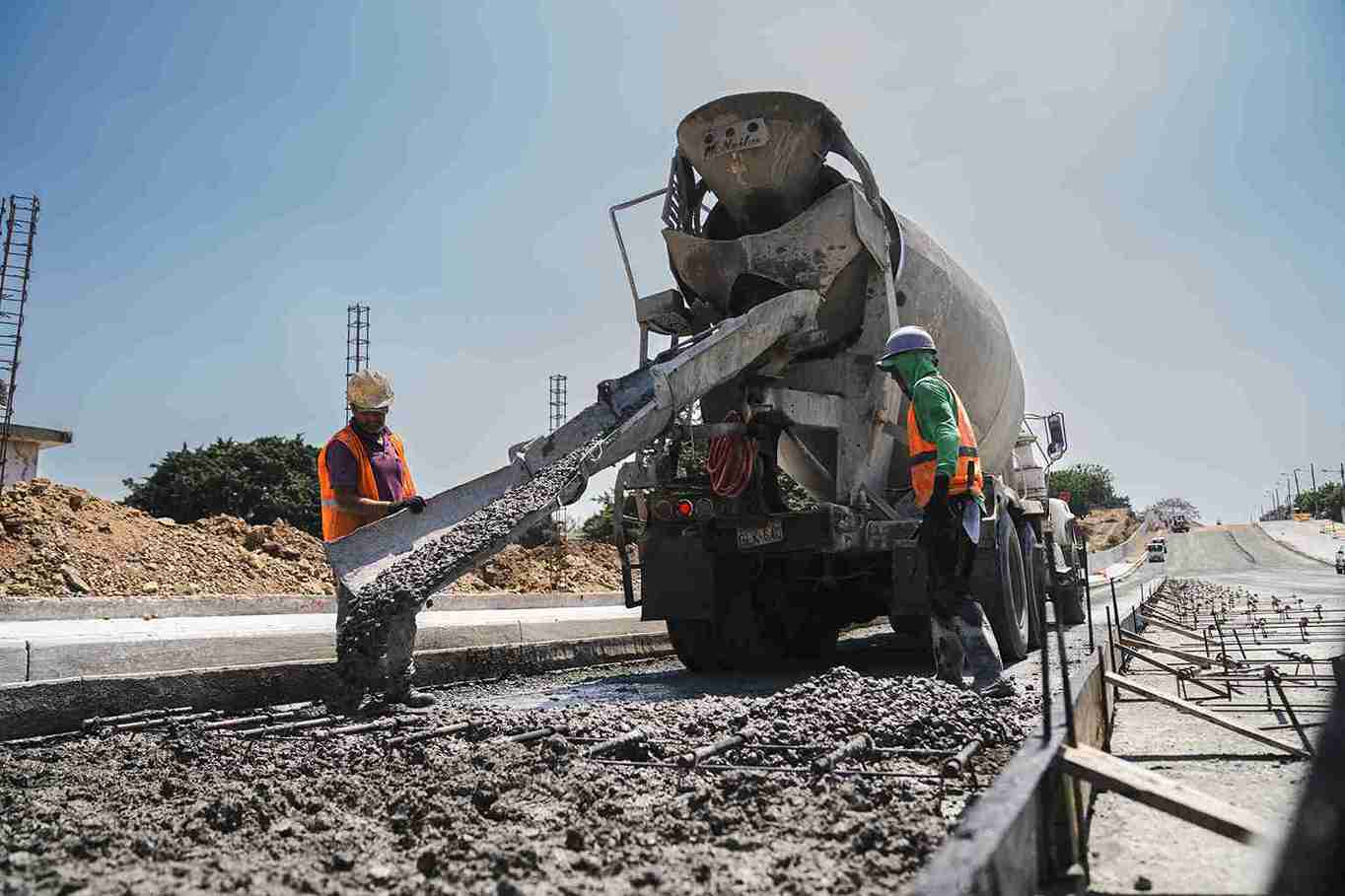 Obreros colocan hormigón en un tramo de la nueva vía, que tiene un avance del 50%.