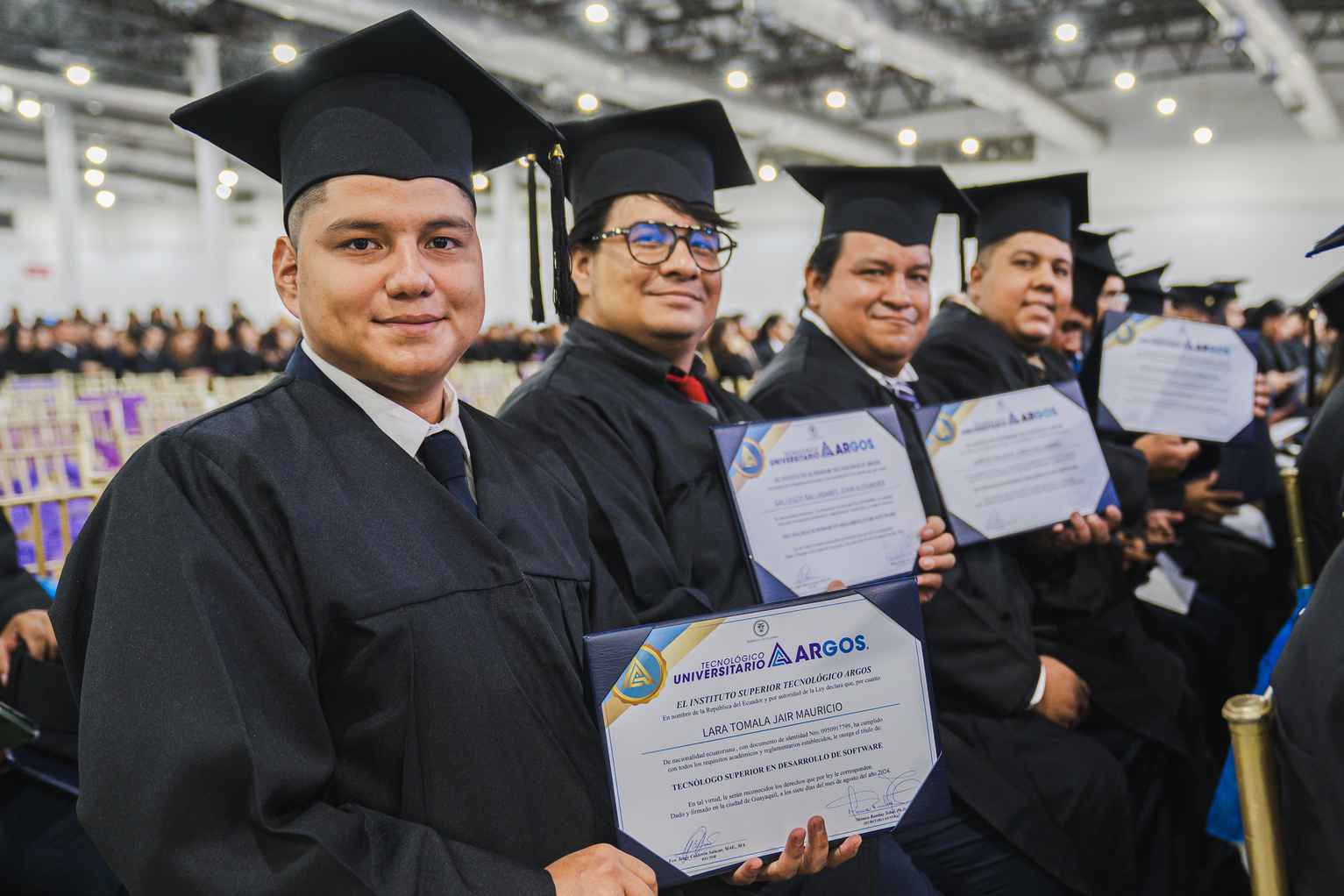 Un grupo de graduados muestras sus títulos.