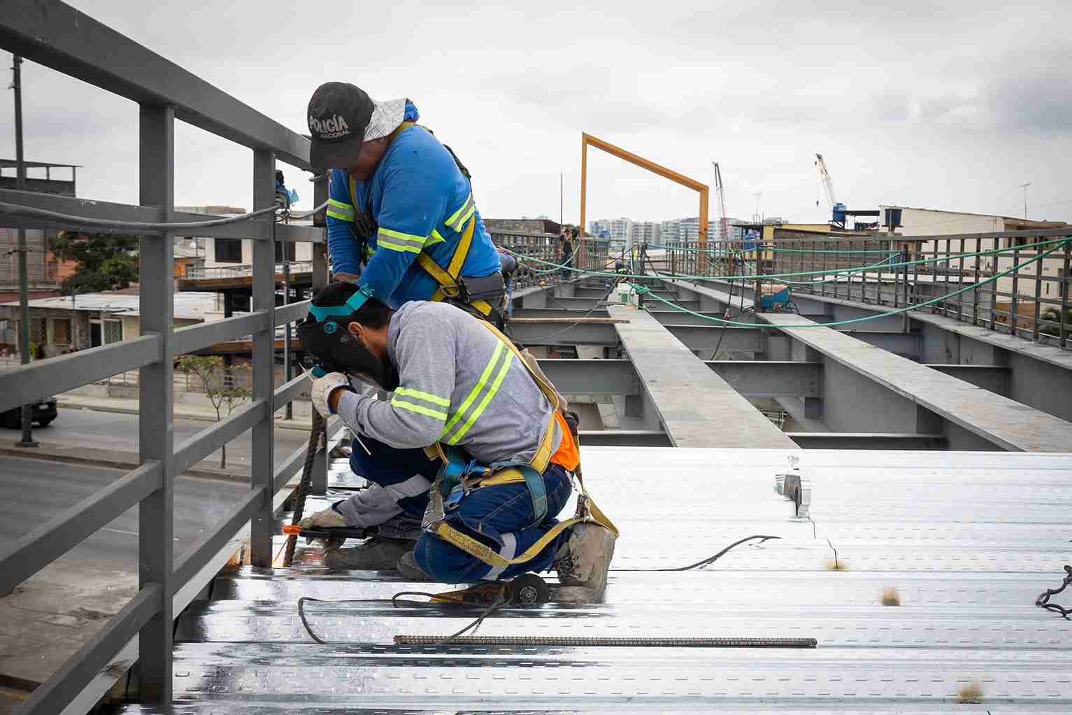 Obreros realizan trabajo de soldadura en la estructura del nuevo paso peatonal.