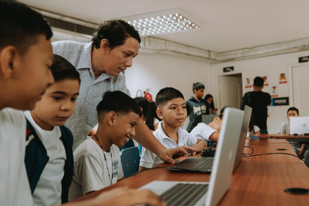 Un docente guía a los estudiantes en el uso de computadoras durante una sesión de nivelación académica en Plaza Colón.